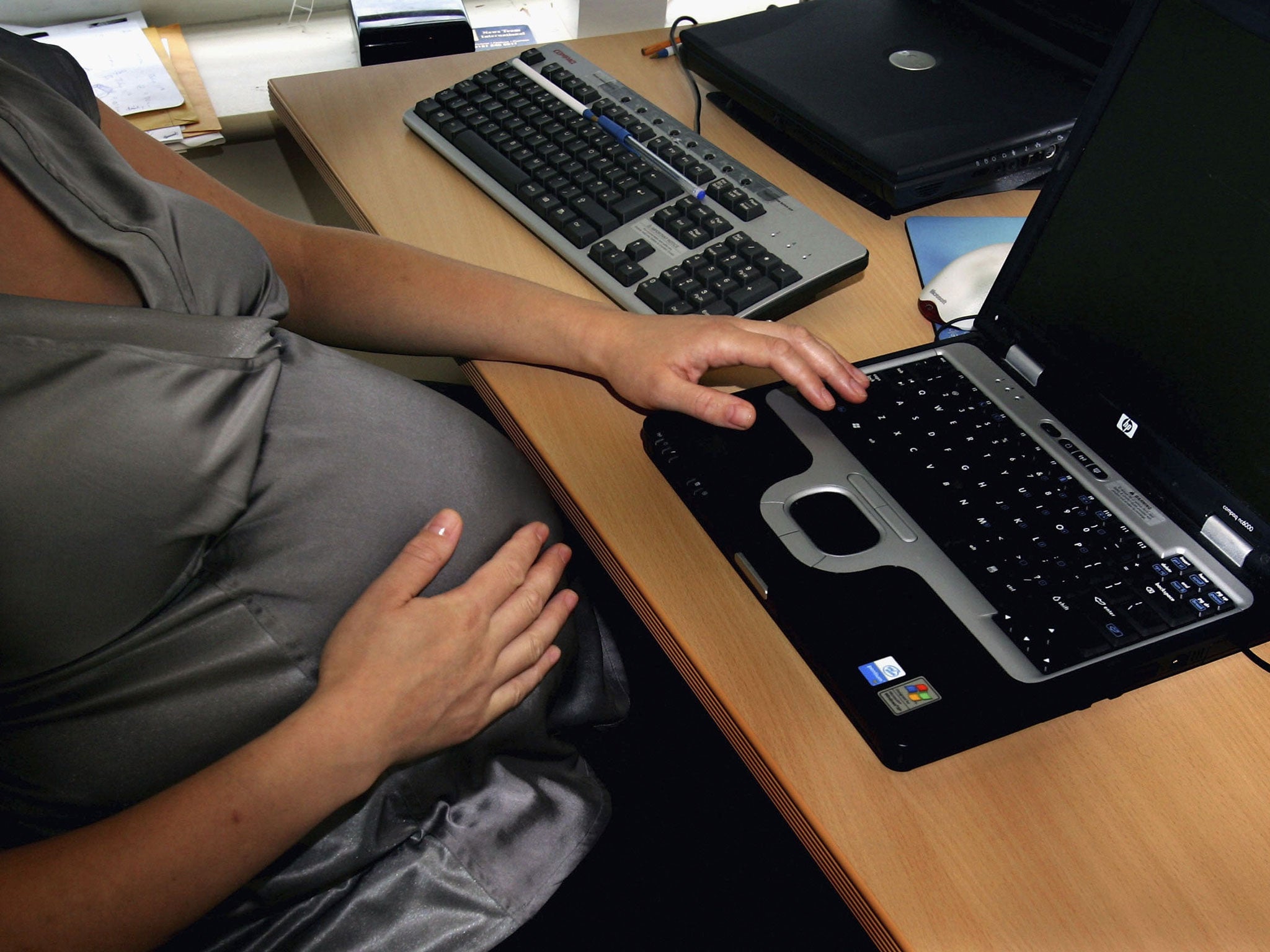In this photo illustration a pregnant woman is seen at the office work station on July 18, 2005 in London, England.