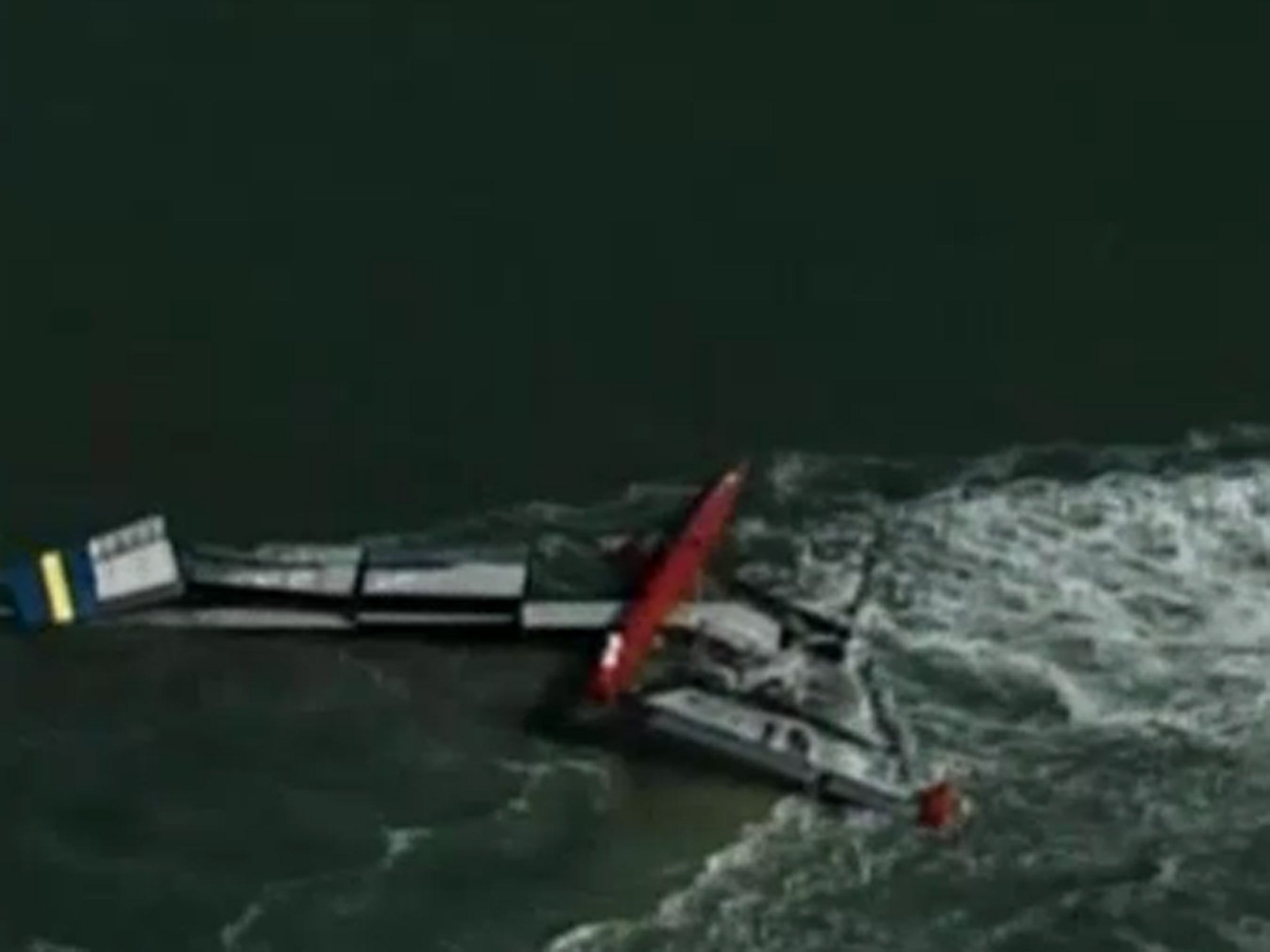 The capsized catamaran is towed back to shore