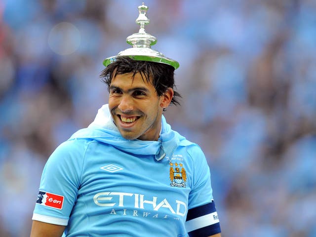 Carlos Tevez with the FA Cup trophy lid upon his head in 2011