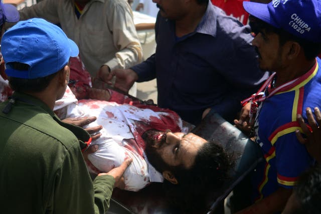 Pakistani volunteers carry an injured blast victim to a hospital following a bomb explosion in Karachi