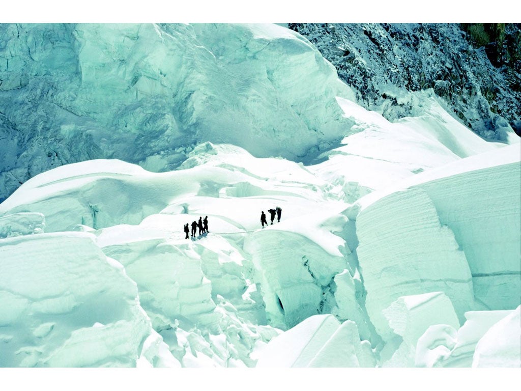 Expedition members cross a crevasse using a light metal sectional ladder