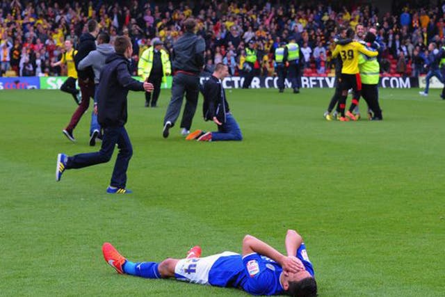 Anthony Knockaert of Leicester lies on the turf after his team's loss to Watford to exit the play-offs, while Watford fans run onto the pitch to celebrate (Michael Regan/Getty Images)