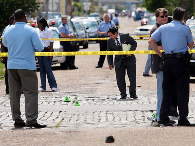 New Orleans police officers investigate the scene at the intersection of Frenchmen and N. Villere Streets in New Orleans after gunfire at a Mother's Day second-line parade