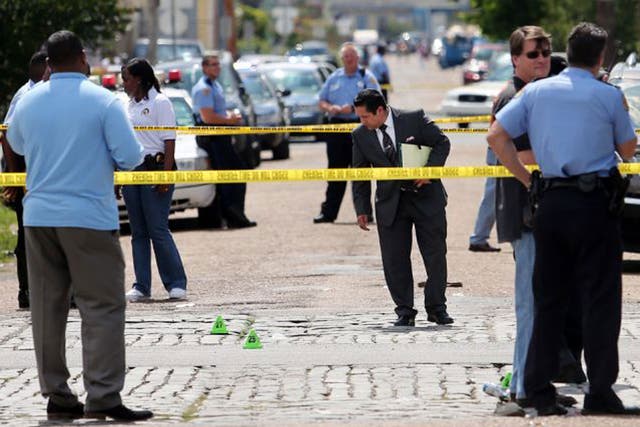 New Orleans police officers investigate the scene at the intersection of Frenchmen and N. Villere Streets in New Orleans after gunfire at a Mother's Day second-line parade