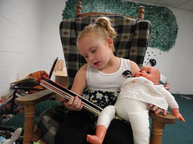 Alana (Honey Boo Boo) reads a book to her baby doll.