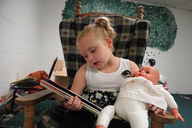 Alana (Honey Boo Boo) reads a book to her baby doll.