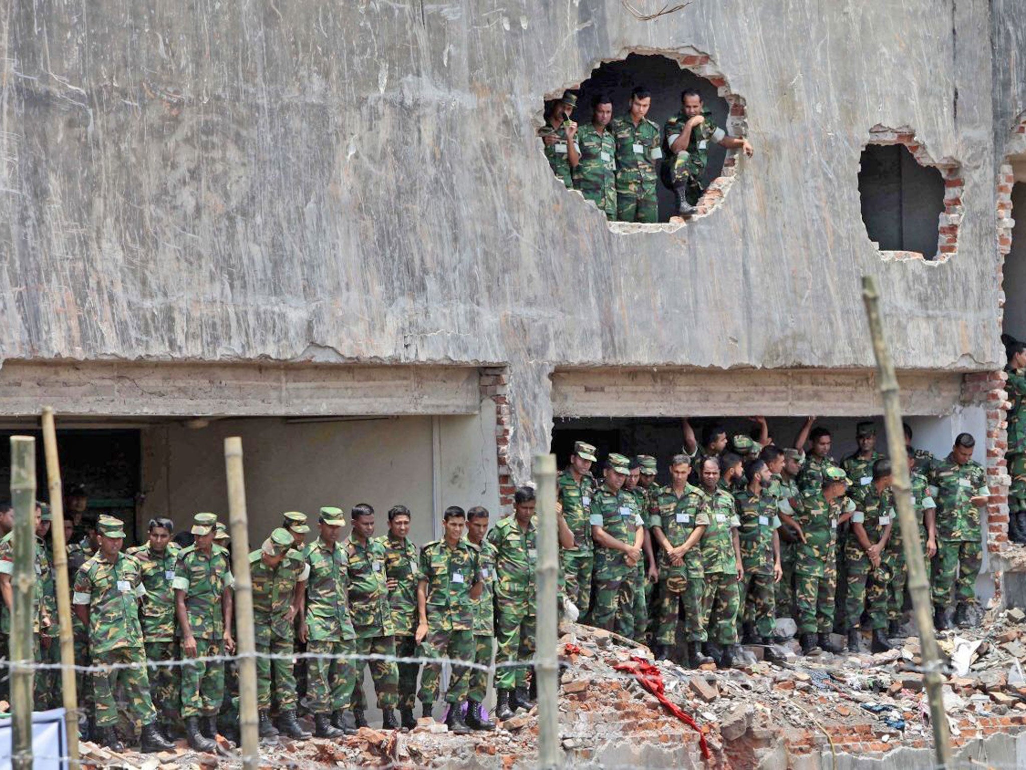 Army soldiers stand at the wreckage of a Bangladeshi garment factory building to offer prayers for the souls of the 1,127 people who died in the Bangladesh disaster last month