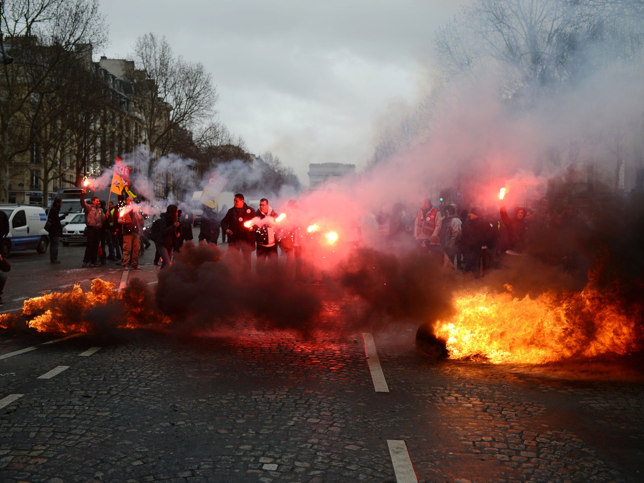 Employees of French auto giant PSA Peugeot Citroen Aulnay plant hold flares in front of fires on March 18, 2013, during a protest outside PSA headquarters in Paris, where an extraordinary central works council is held at the same time to present the group's restructuring plans to trade union representatives. This extraordianry council was focused upon the closure by 2014 of the group's plant in Aulnay-sous-Bois, currently providing 2,800 jobs, and upon the 1,400 jobcuts planned in its plant in Rennes