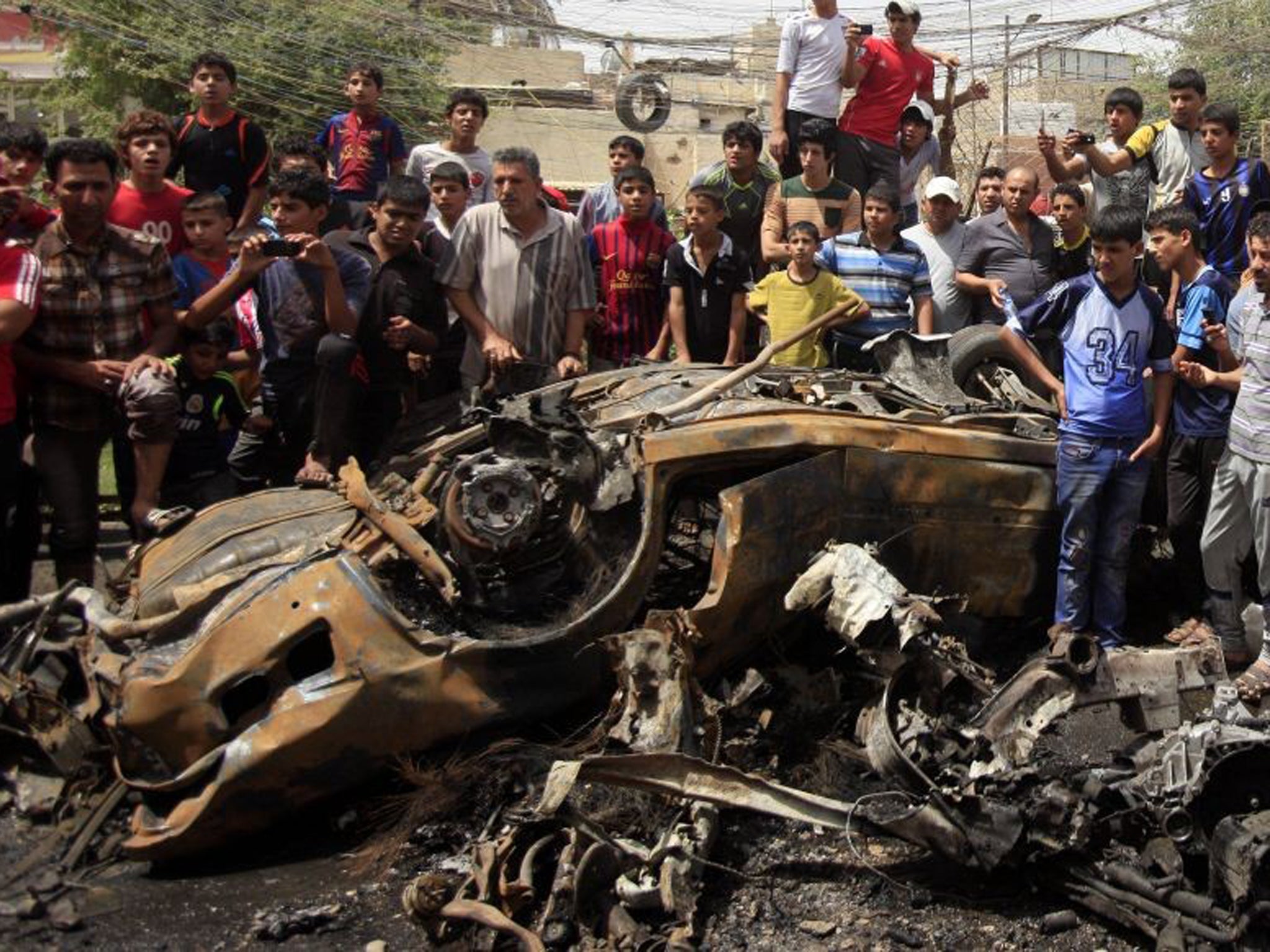 Residents gather around the bomb site in Sadr City