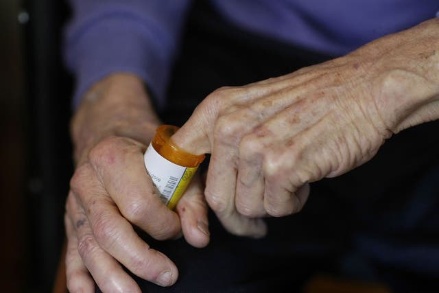 A man reaches into a medicine bottle as he takes prescription pills.
