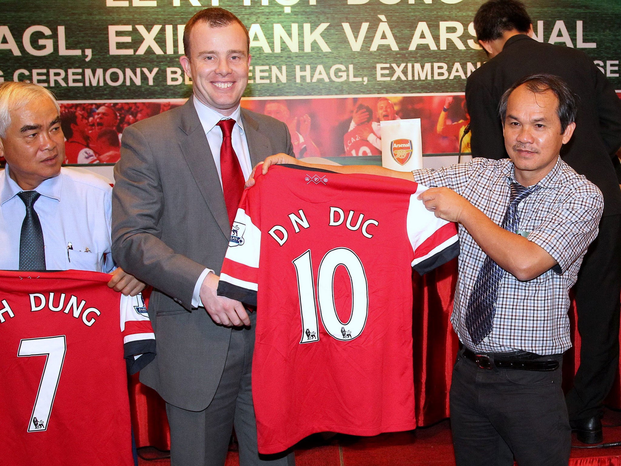 An Arsenal official offers an Gunners jersey to Doan Nguyen Duc
