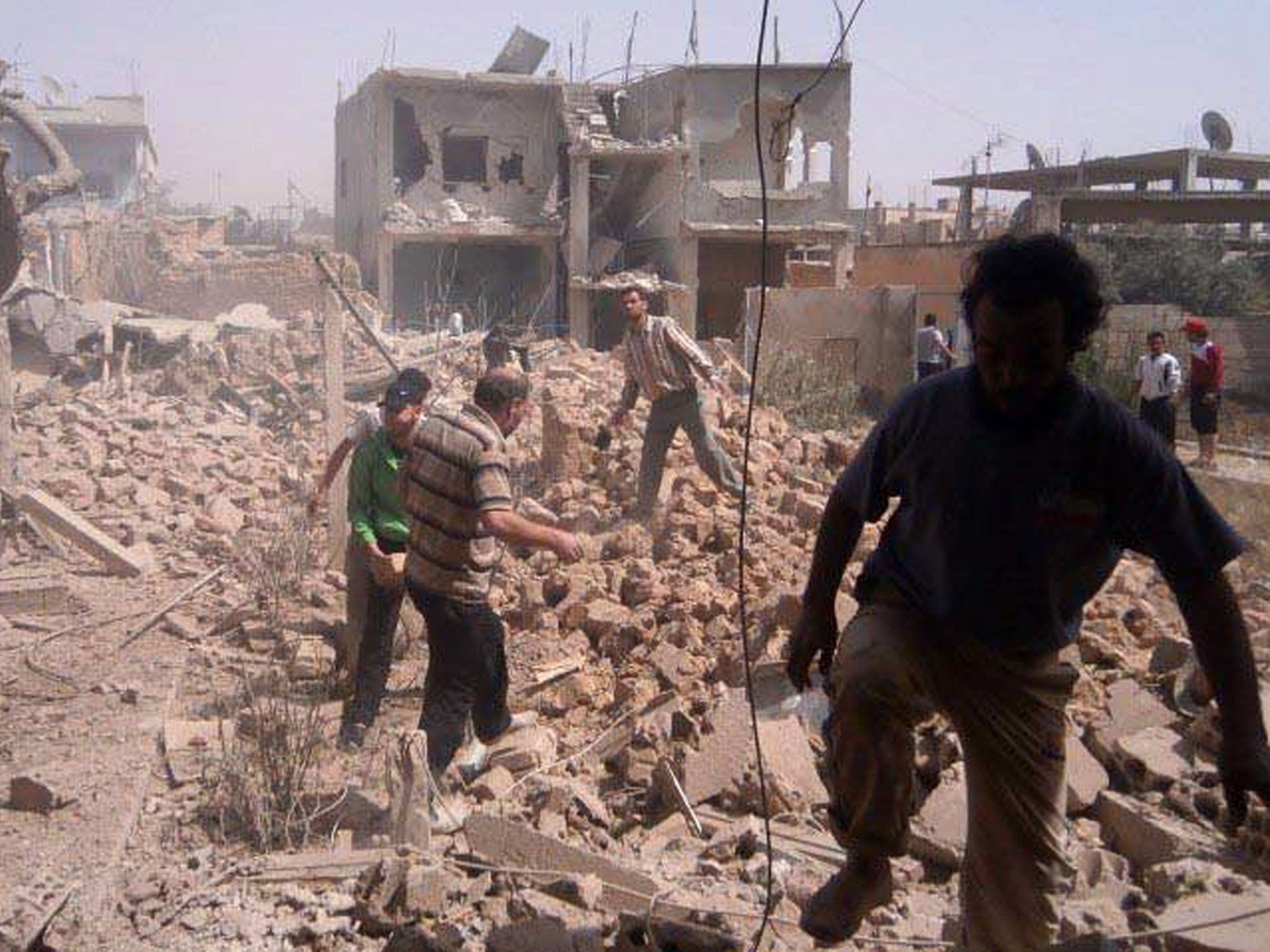 People in Qusair inspect the damage caused by government air strikes