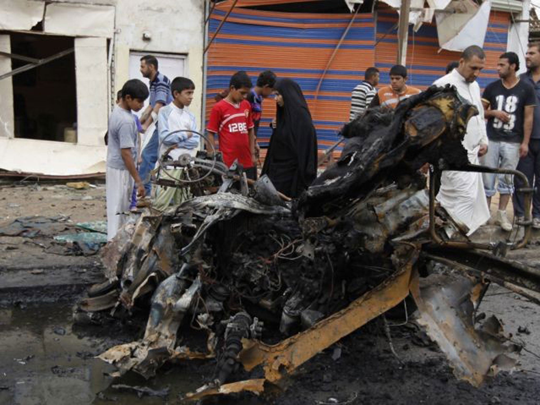 Residents gather at the site of a car bomb attack at the Kamaliya district in Baghdad