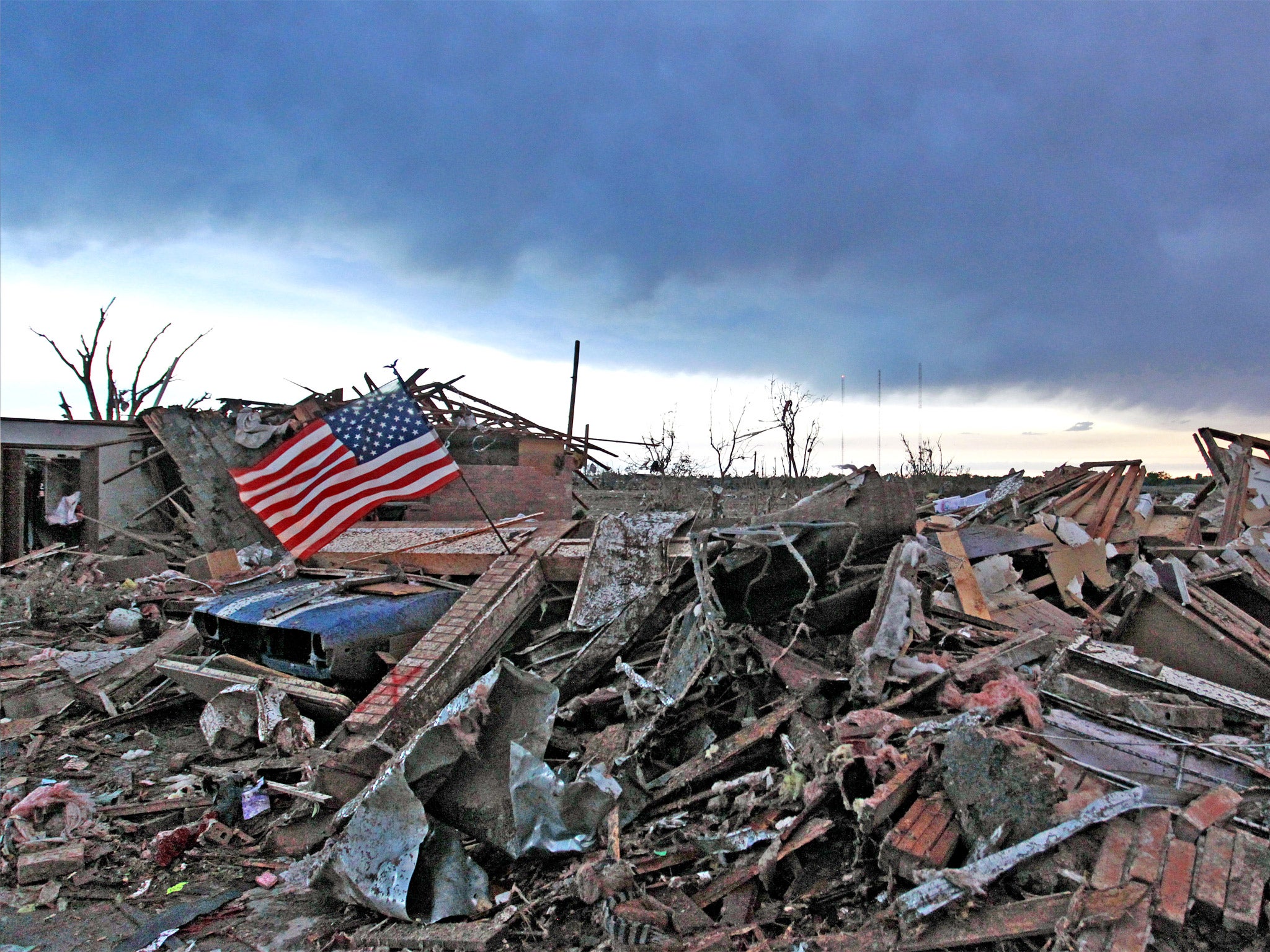 An American flag blows in the wind at sunrise atop the rubble of a destroyed home