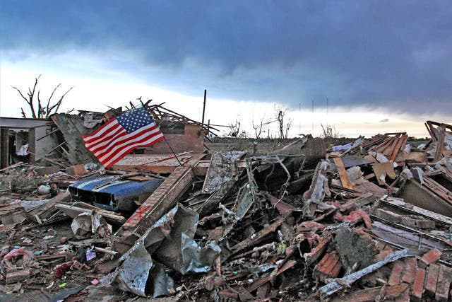 An American flag blows in the wind at sunrise atop the rubble of a destroyed home