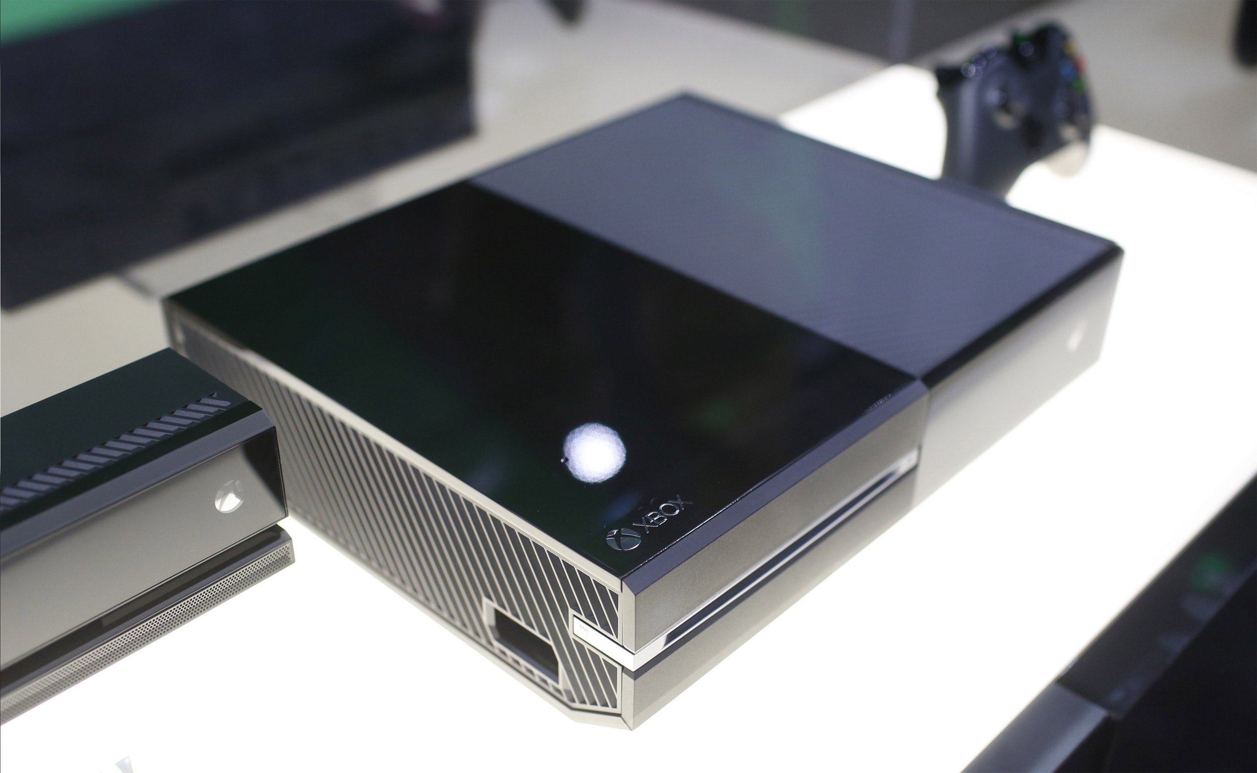 The Xbox One is shown with its controller (right) and a Kinect bar (left)