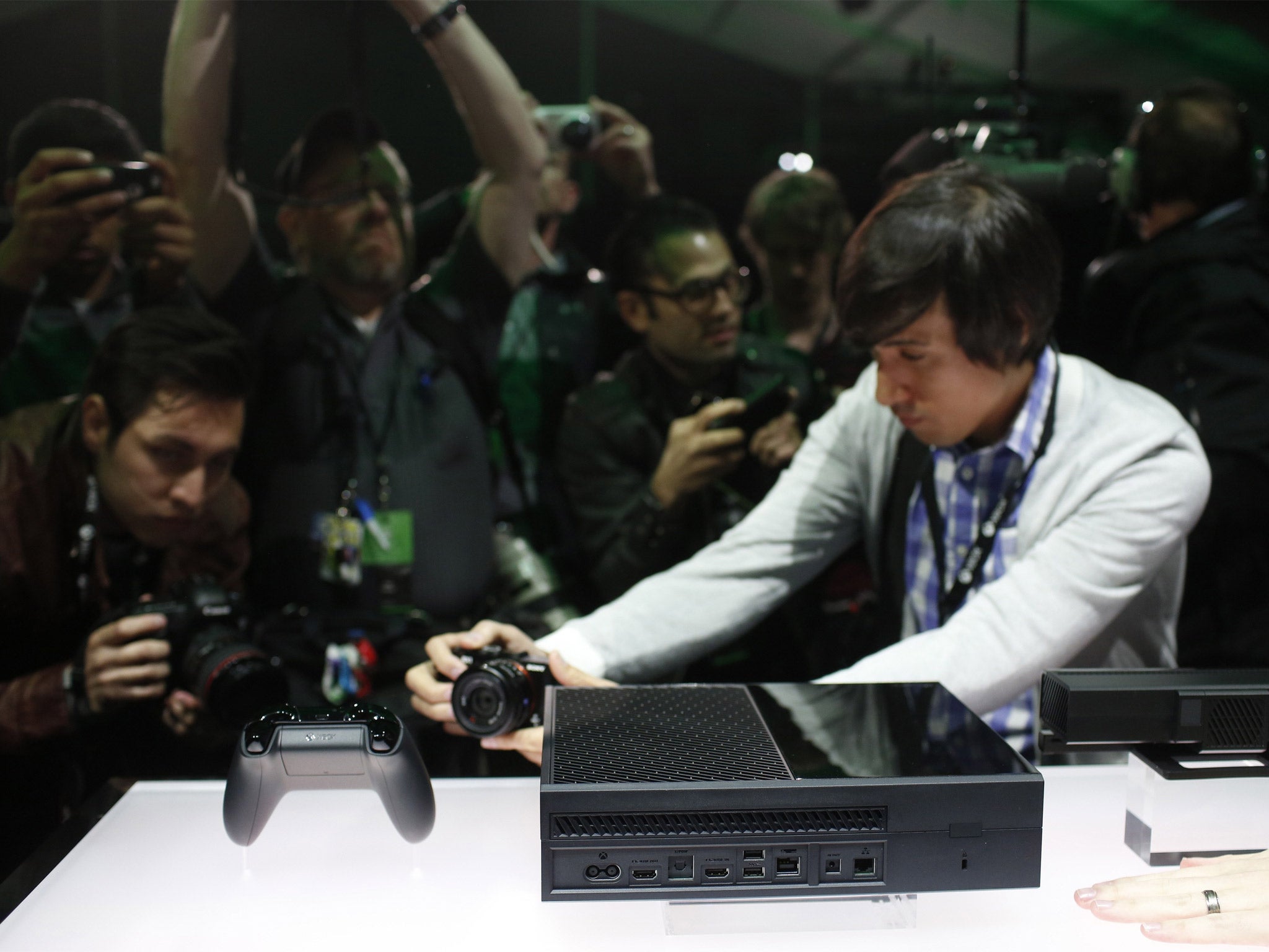Members of the media photograph the Xbox One and its controller