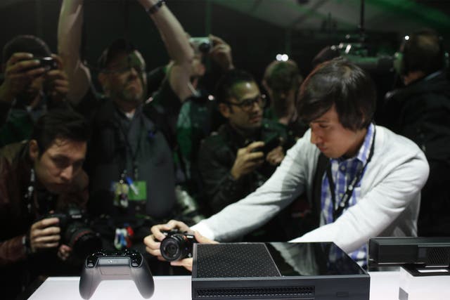 Members of the media photograph the Xbox One and its controller 