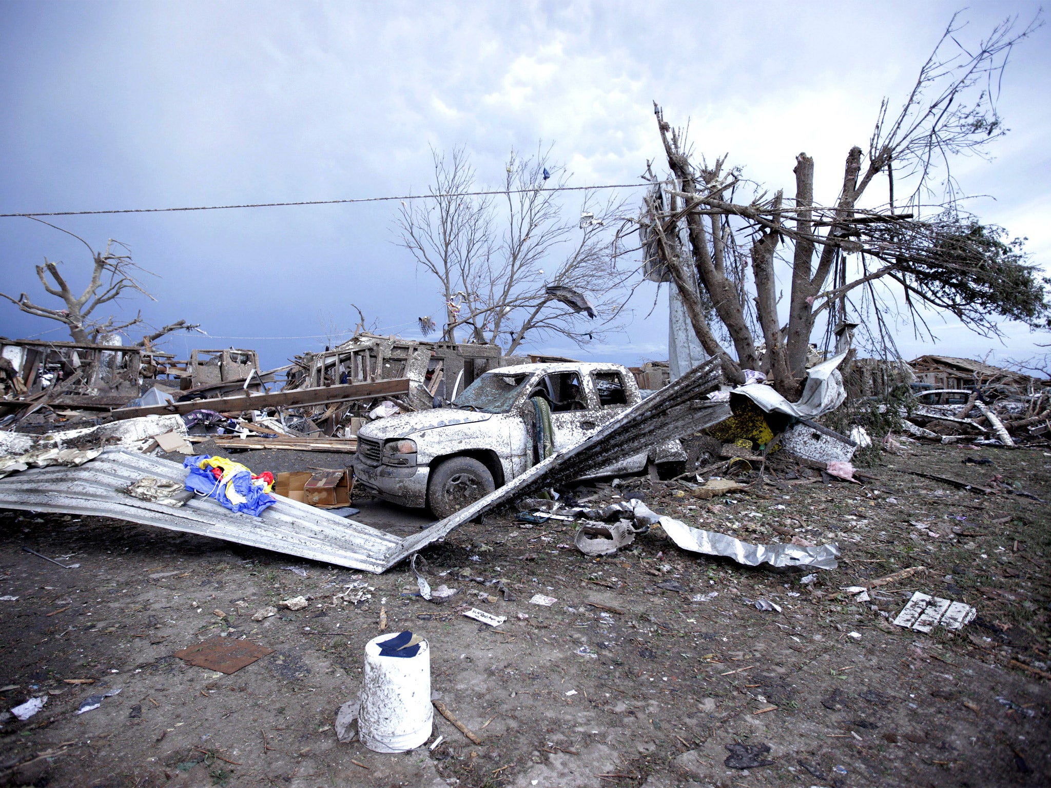 Piles of debris and cars lie around a home destroyed by the tornado