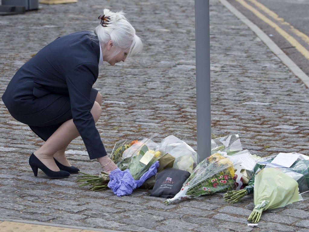 A woman places flowers outside the Royal Military Barracks, near the scene where a man was killed in Woolwich
