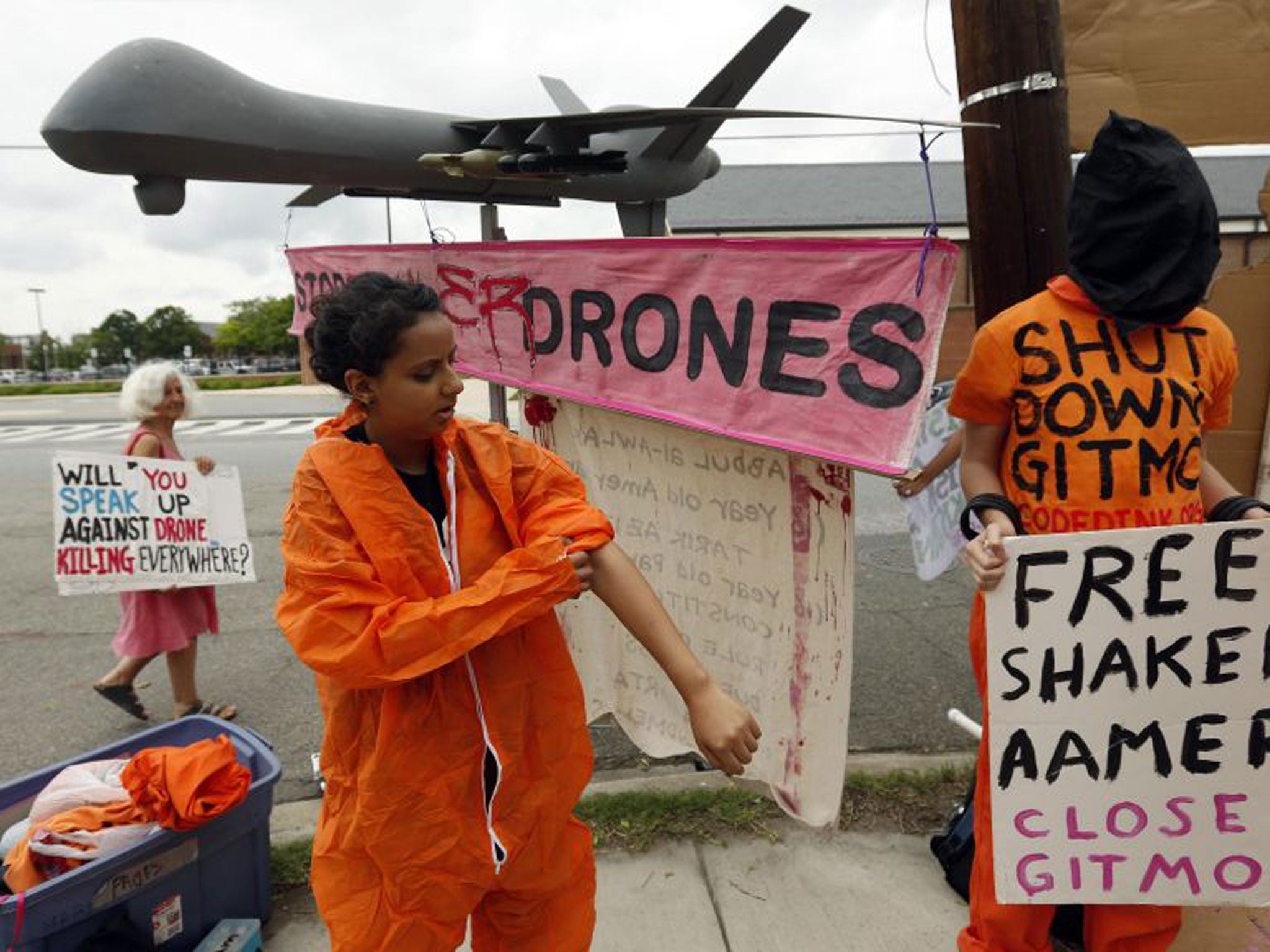 A demonstrator puts on a prison-style jumpsuit as she joins a protest beside a mock drone at the gates of Fort McNair where President Barack Obama will speak at the National Defense University in Washington