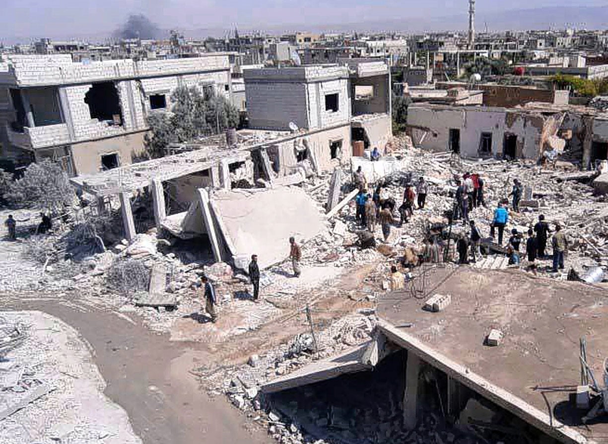 People from Qusair gather near houses destroyed by a Syrian forces air strike last week.