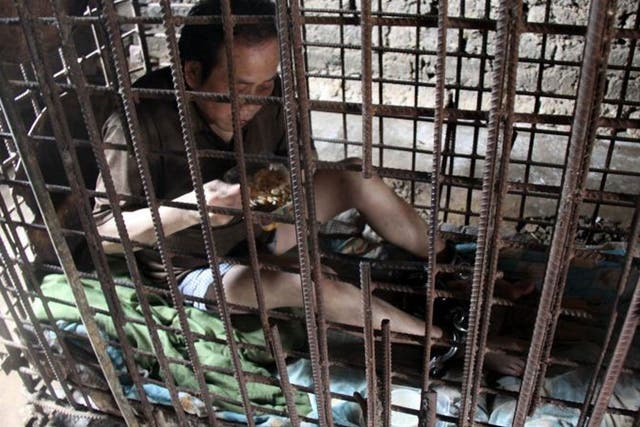 Wu Yuanhong eating in his cage and shackles
