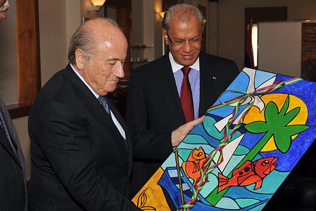 The President of FIFA, Sepp Blatter (L) holds up a painting by Mauritian painter Vaco Baissac