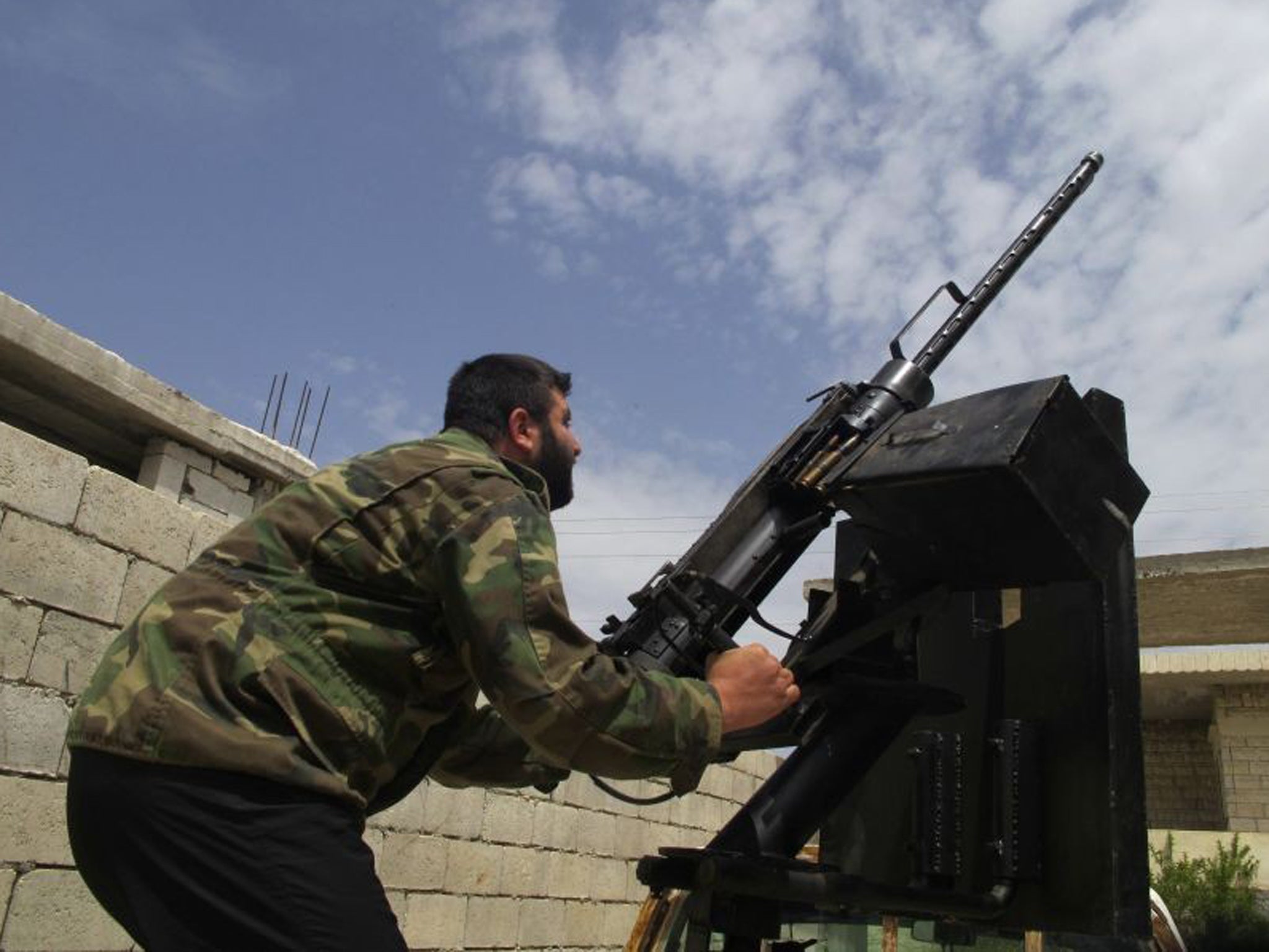 A Free Syrian Army fighter takes position by pointing an artillery weapon towards the sky in Idlib