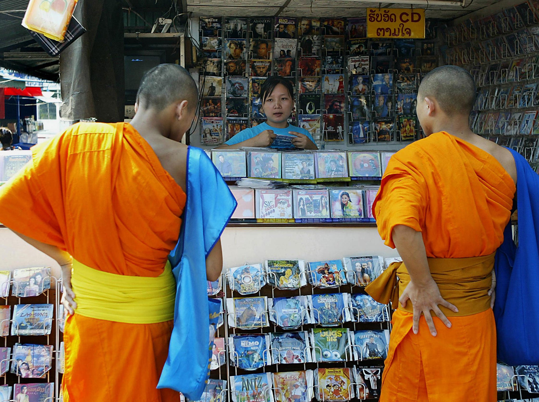 Two monks check out a CD shop selling pirated movies and music albums in Vientiane, the Laotian capital, 02 December 2004.