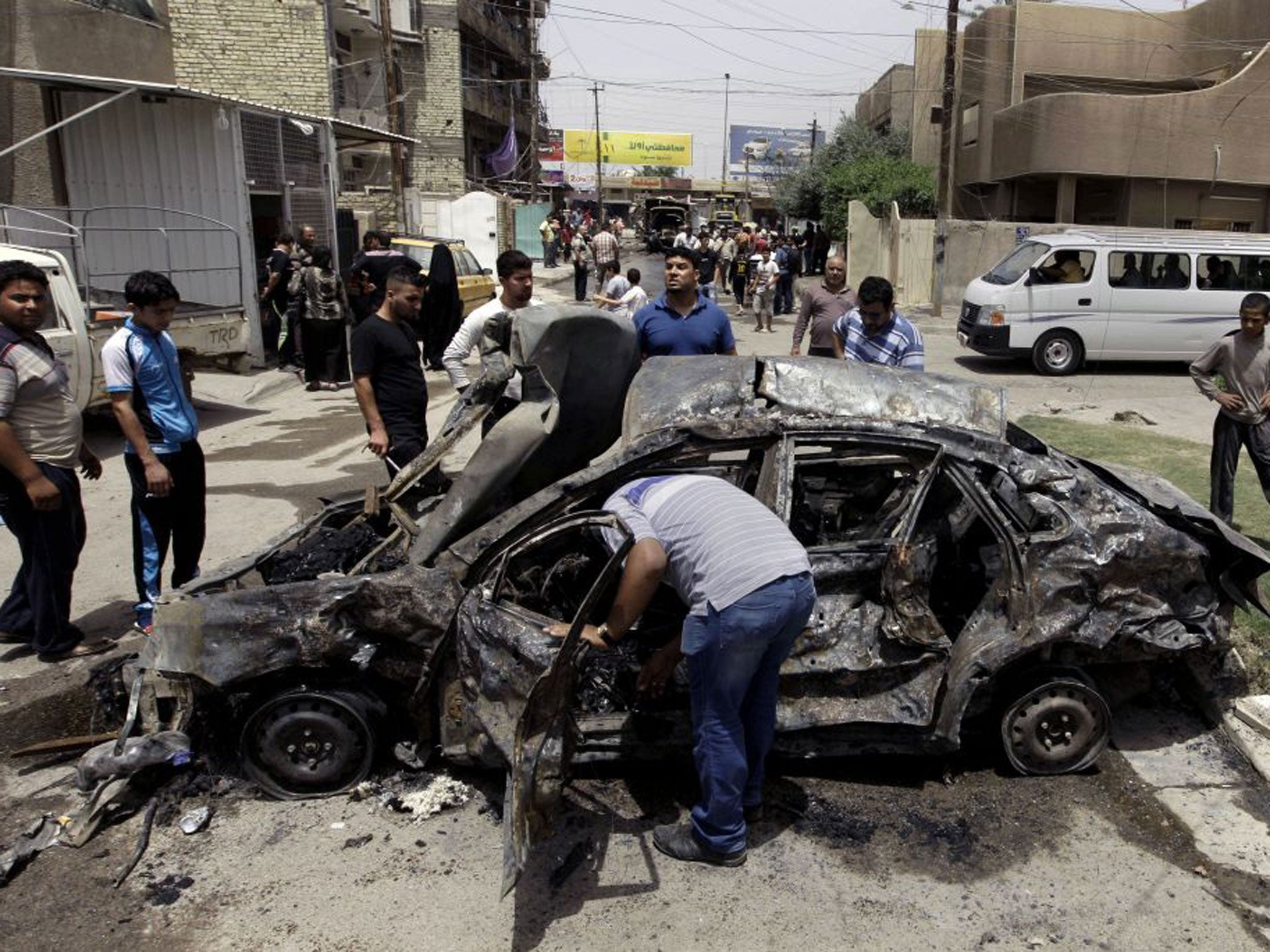 Civilians inspect the site of a car bomb attack near a popular restaurant in northern Baghdad