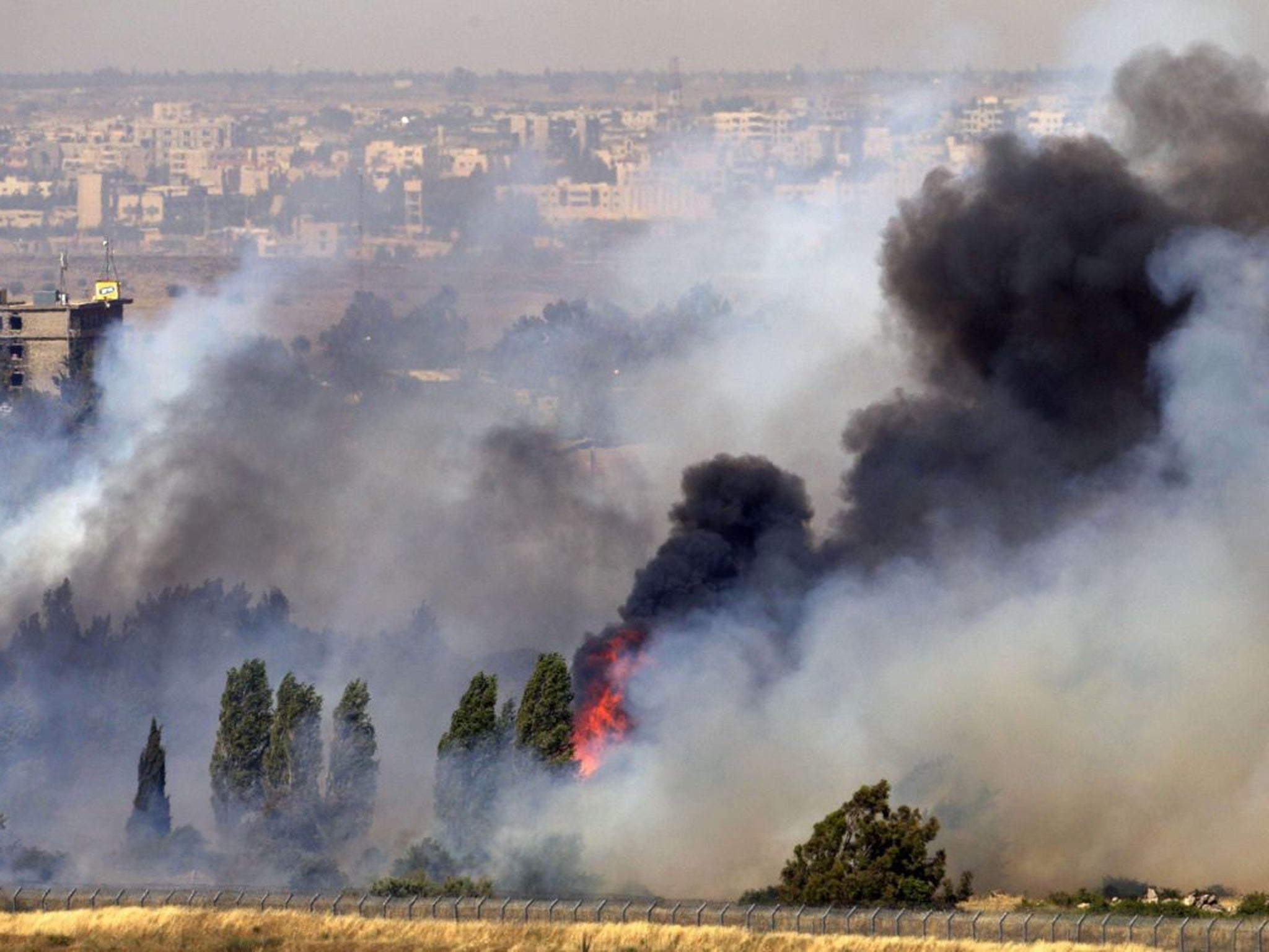 A picture taken on June 6, 2013 from the Israeli side along the Israel-Syria ceasefire line in the Golan Heights shows smoke billowing from a fire caused by clashes between Syrian rebels and forces loyal to the regime near the Quneitra crossing