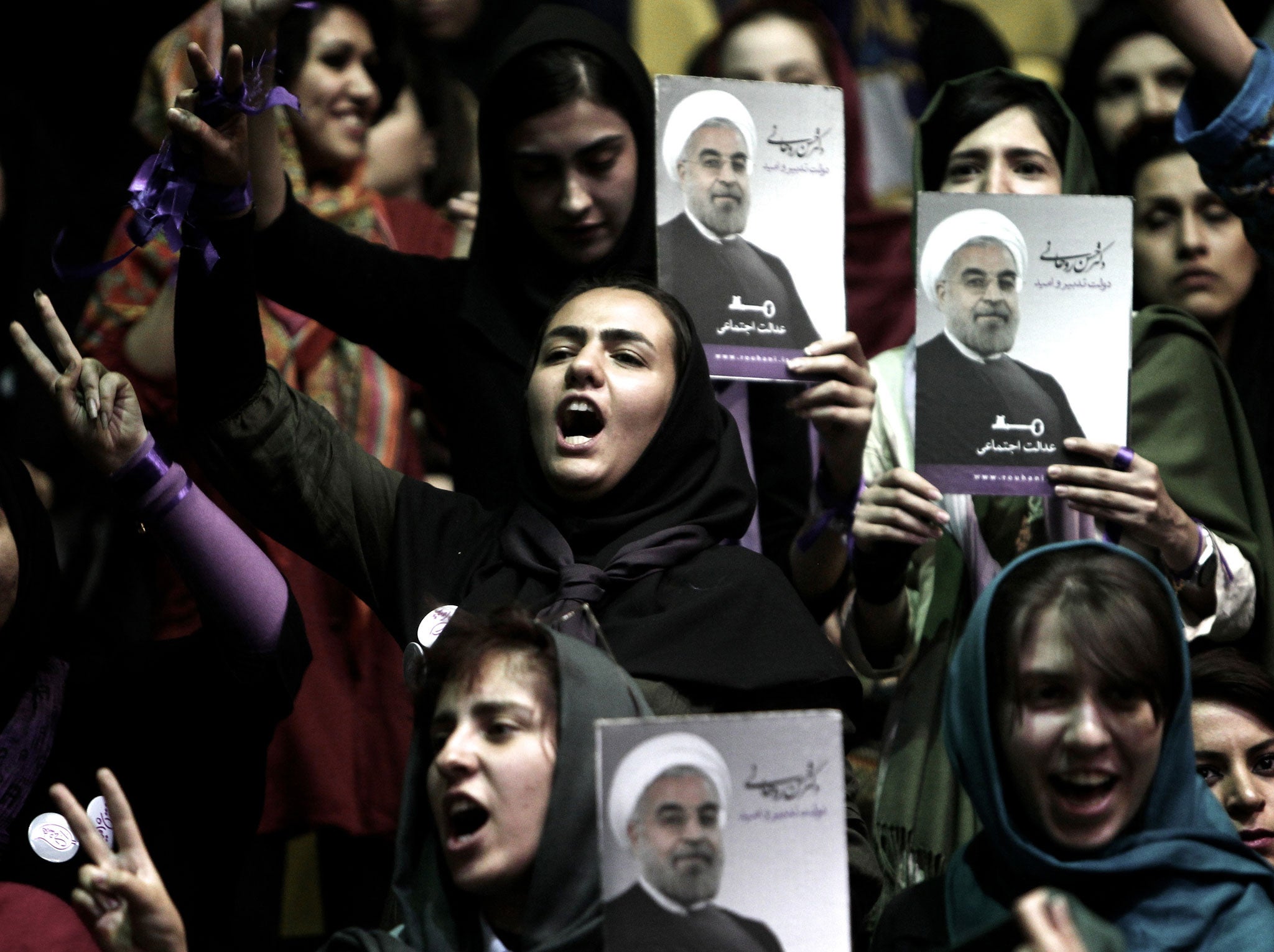 Iranian supporters of Hassan Rowhani, a moderate Iranian presidential candidate and former top nuclear negotiator, hold his portrait during a campaign rally in downtown Tehran on June 8, 2013.