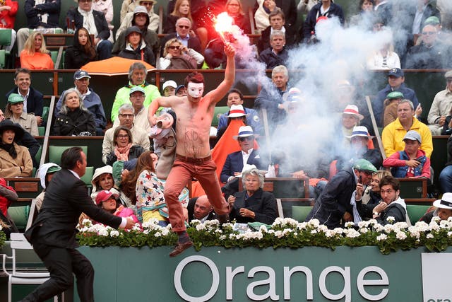 A protester runs onto court with a lit flare before the start of a game in the Men's Singles final
