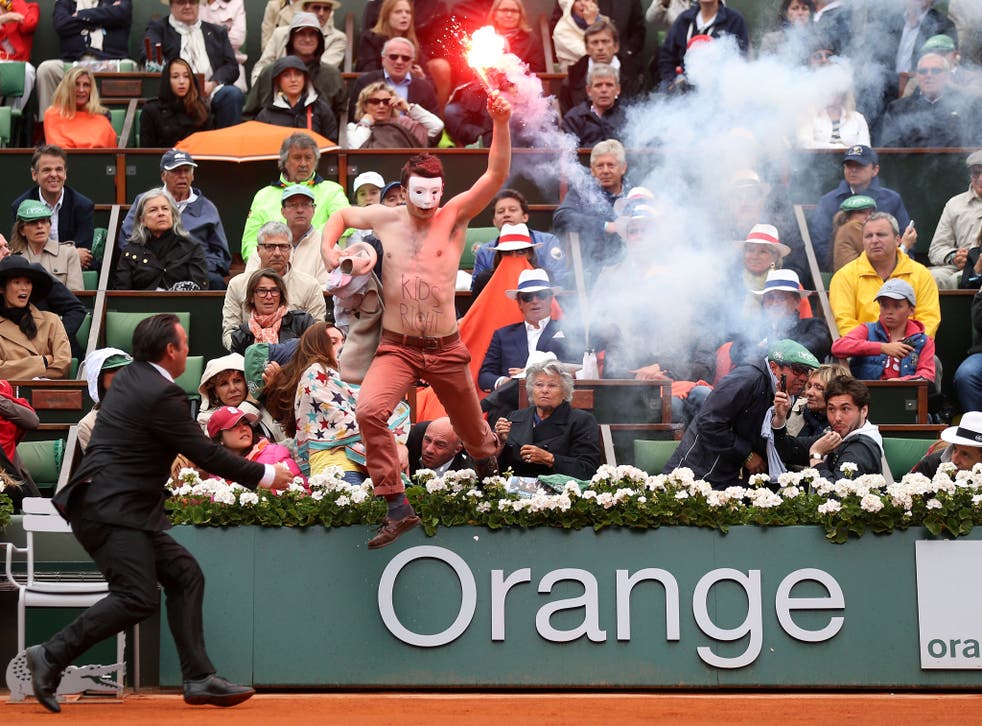 A protester runs onto court with a lit flare before the start of a game in the Men's Singles final