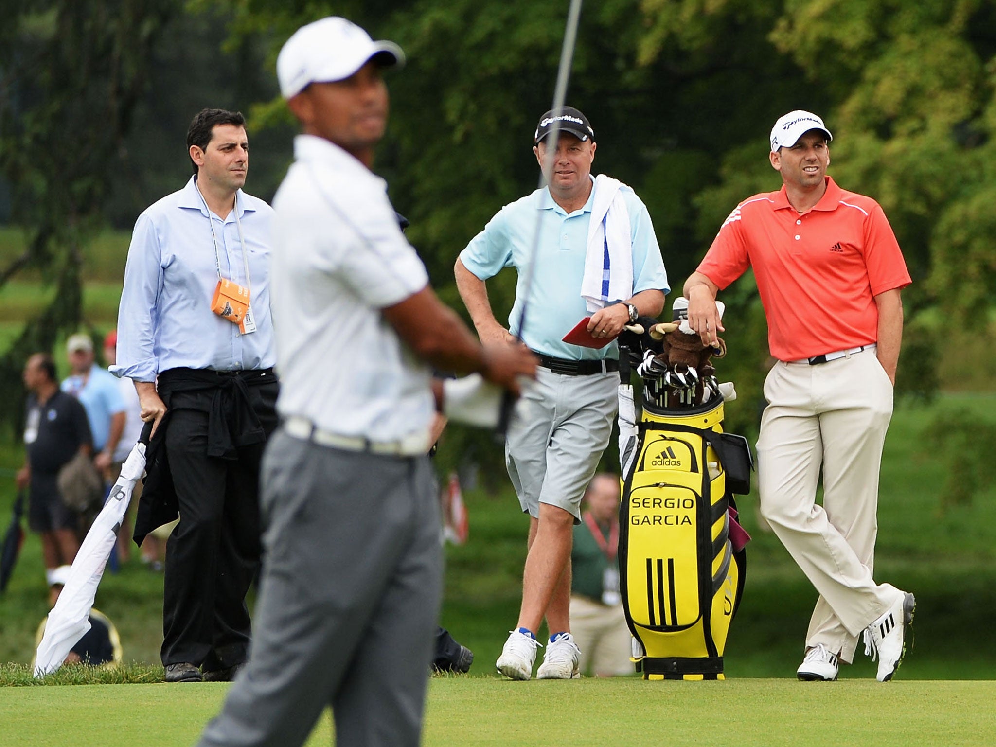 Sergio Garcia (right) watches Tiger Woods hit a shot on the practice range at Merion Golf Club