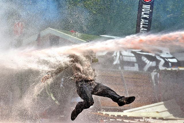 A protestor is hit by water sprayed from a water cannon during clashes in Taksim Square