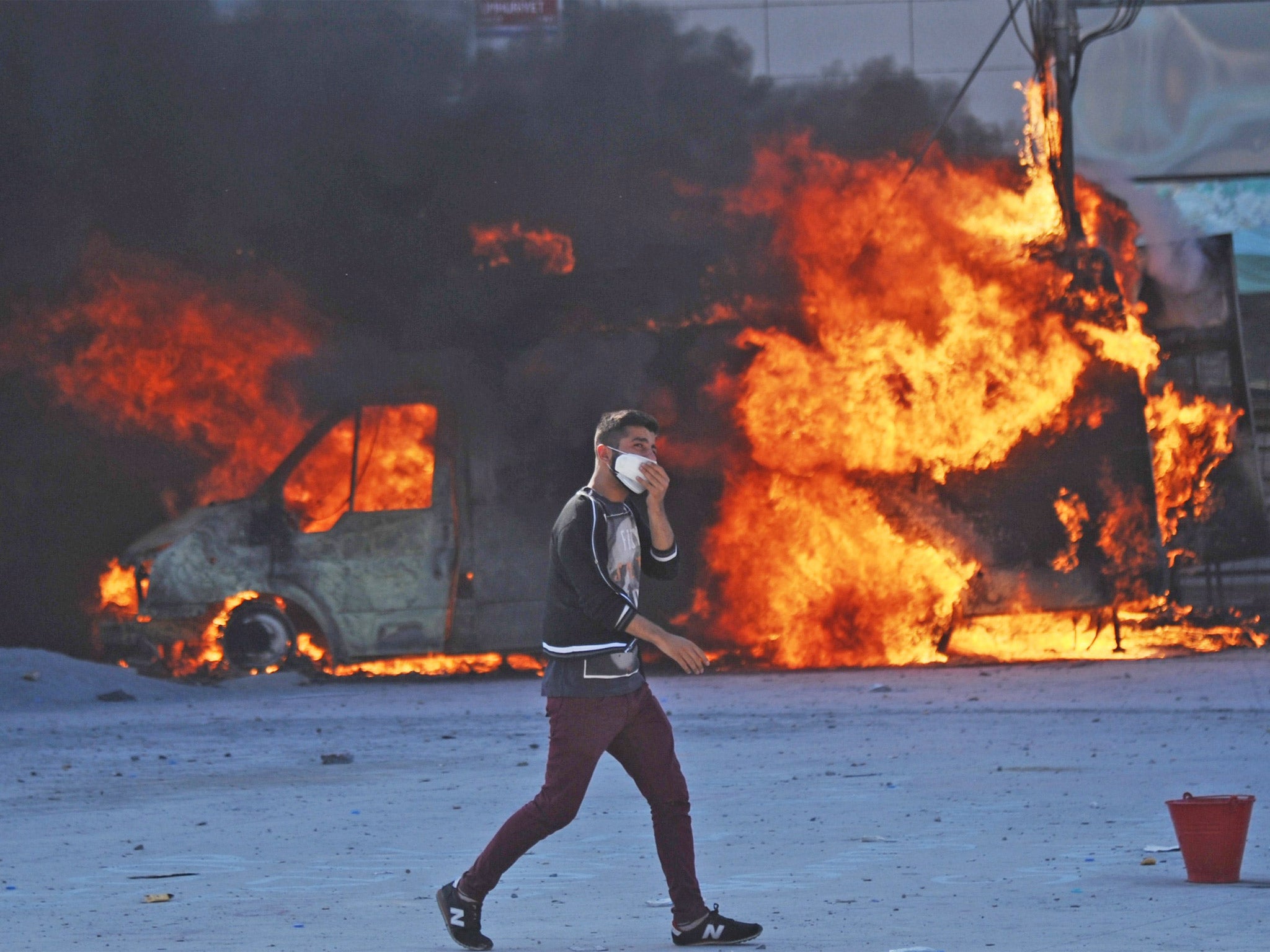 A man walks in front of a burning car during clashes with police on Taksim square