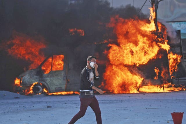 A man walks in front of a burning car during clashes with police on Taksim square 