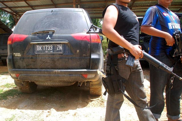 Indonesian policemen stand guard next to a car reportedly used by a British man kidnapped in East Aceh