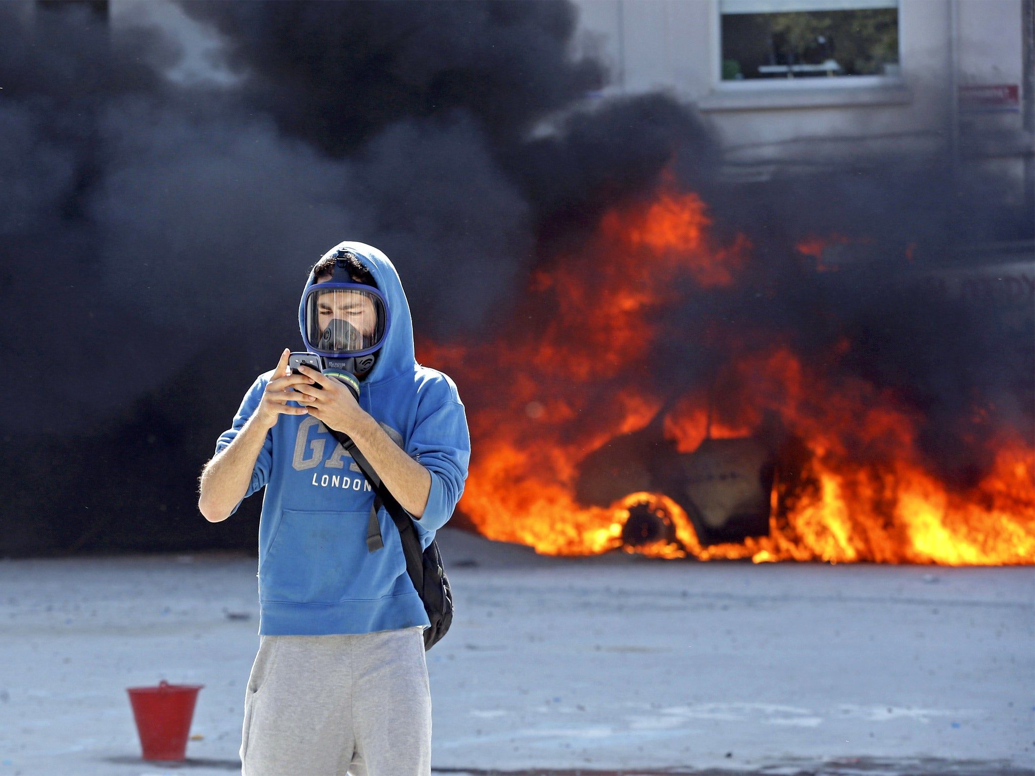 A protester stops to use his smartphone during the riots at Taksim Square in Istanbul