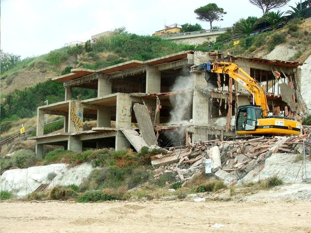 A bulldozer starts to tear its way through the 'ecomonster' at Scala dei Turchi near Agrigento, Sicily