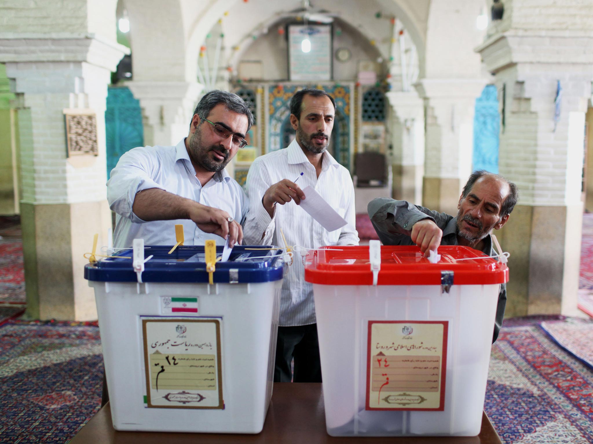 Iranian men cast their ballots during presidential elections at a polling station in Qom, 125 kilometers (78 miles) south of the capital Tehran, Iran