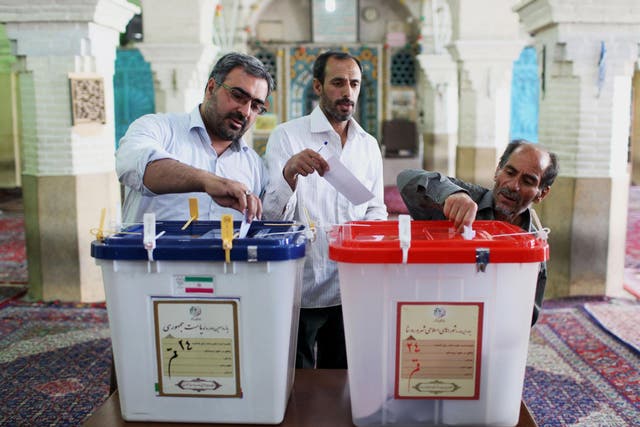 Iranian men cast their ballots during presidential elections at a polling station in Qom, 125 kilometers (78 miles) south of the capital Tehran, Iran
