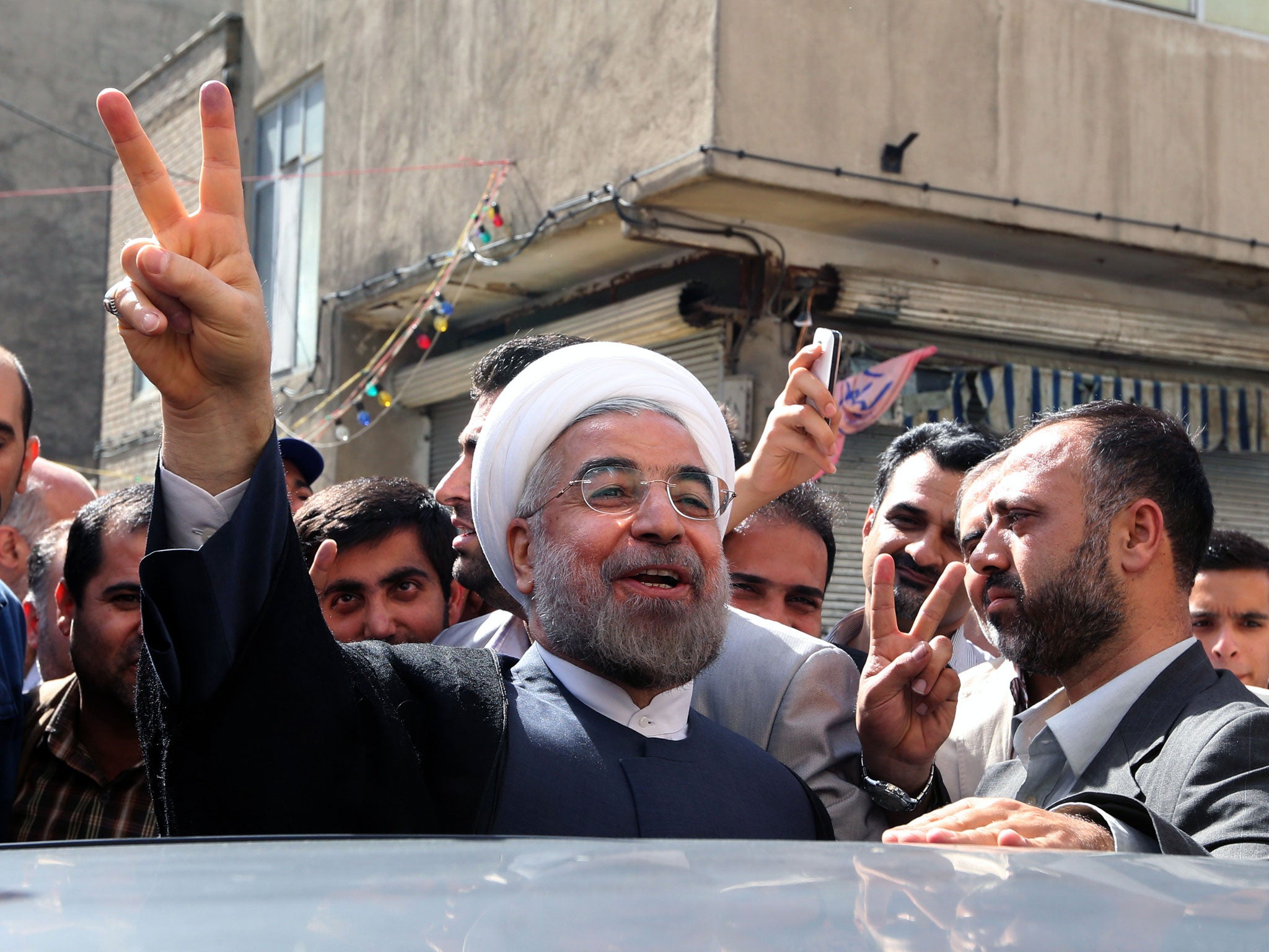 Iranian moderate presidential candidate, Hassan Rowhani flashes the sign of victory as he leaves a polling station after voting on June 14, 2013 in Tehran