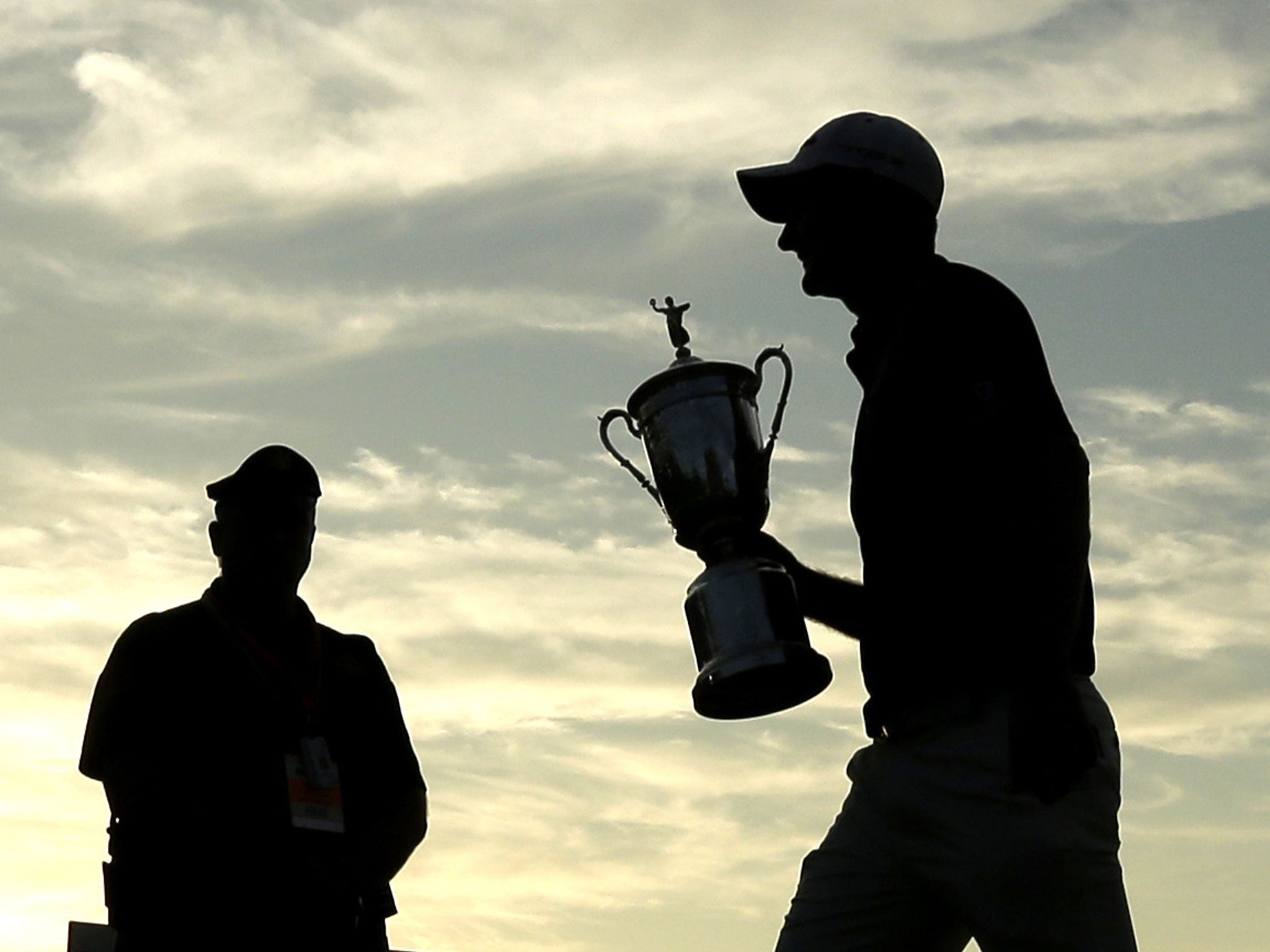 Justin Rose carries the US Open trophy across the 18th green after his victory