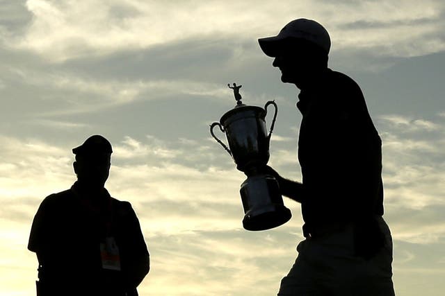 Justin Rose carries the US Open trophy across the 18th green after his victory