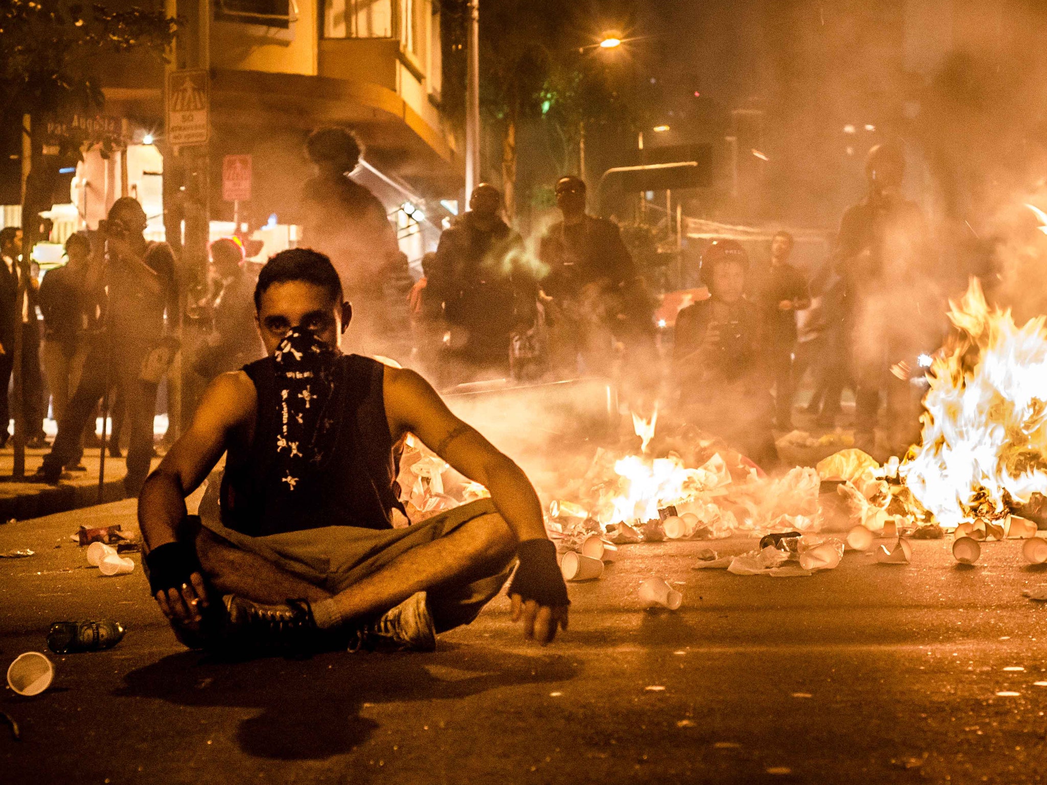 A protester sits amid flames and wreckage in Sao Paulo