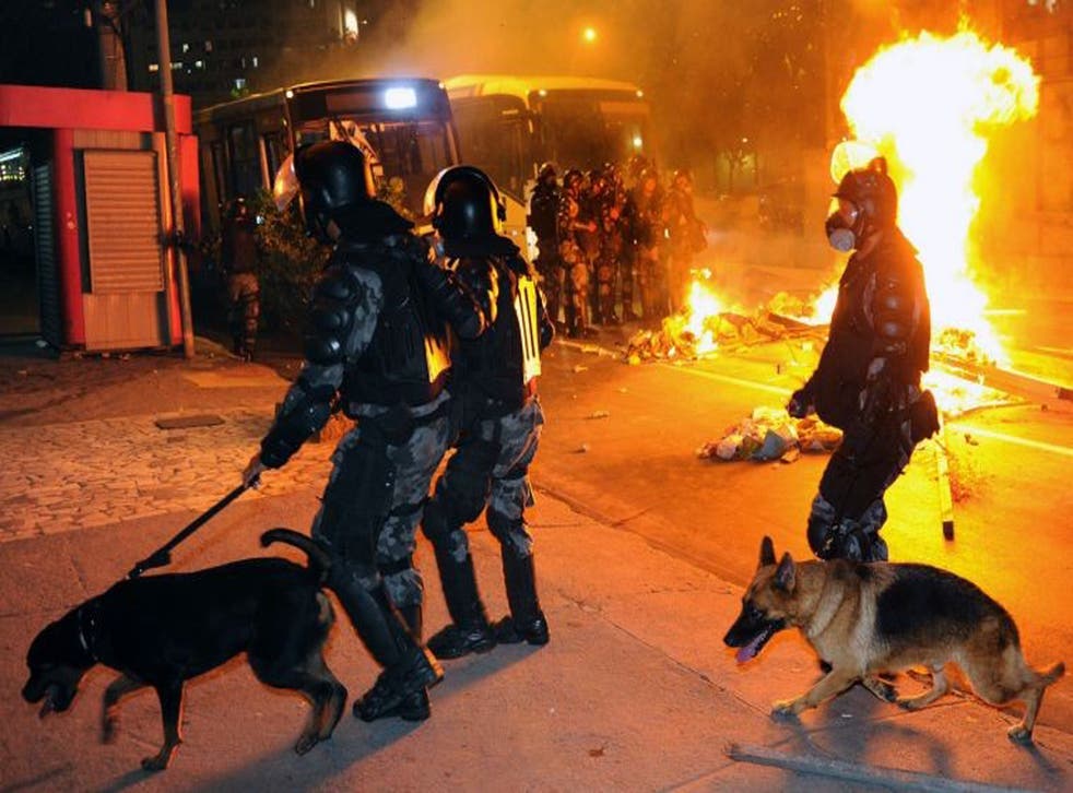 Riot policemen walk next to a fire barricade in downtown Niteroi, near Rio de Janeiro