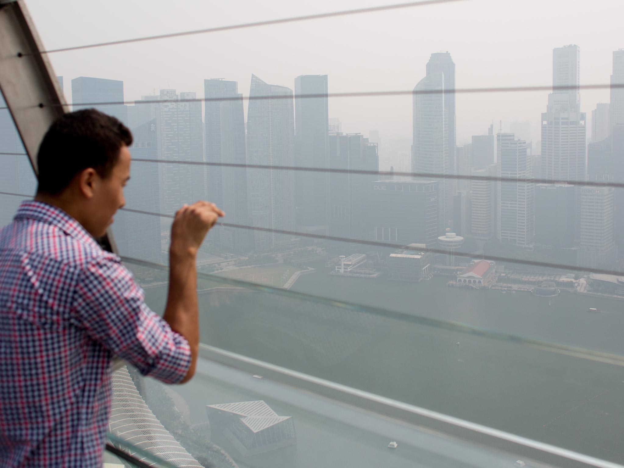 A man looks out over the smoke filled Singapore skyline on in Singapore. The Pollutant Standards Index (PSI) rose to the highest level on record reaching 371